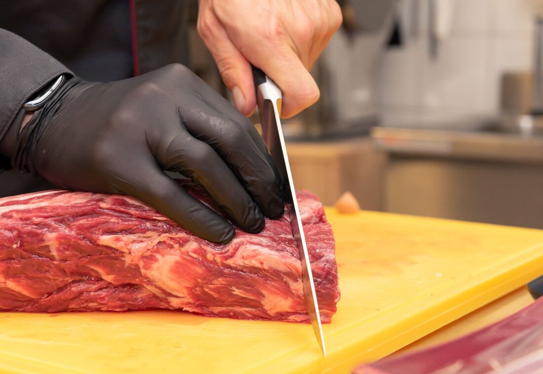 Großes Stück Fleisch wird mit Messer aufgeschnitten