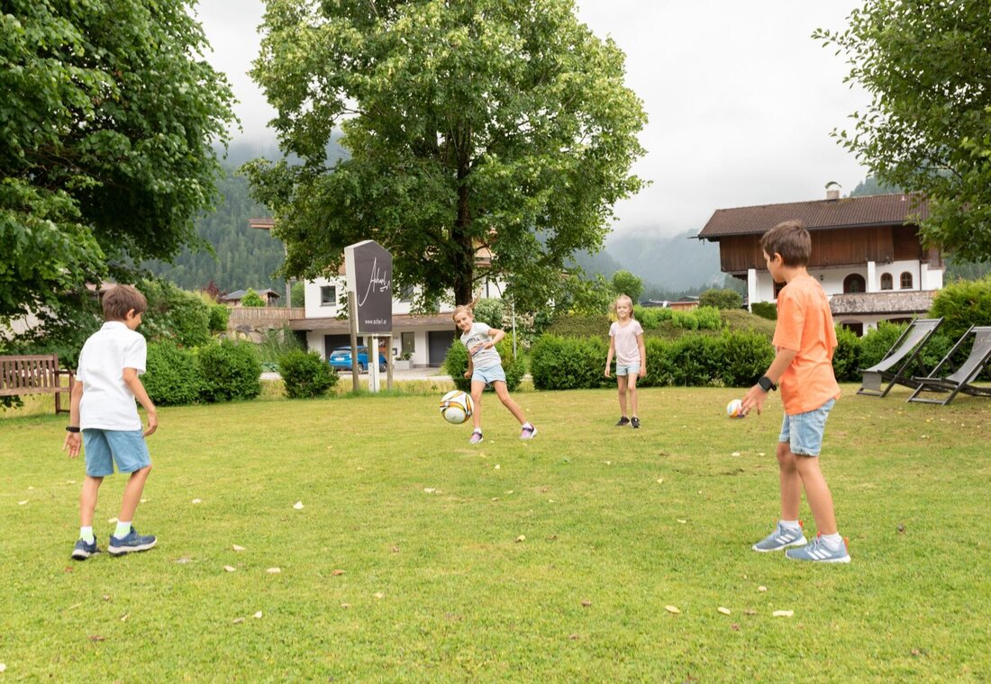 Vier Kinder spielen Fußball im Garten