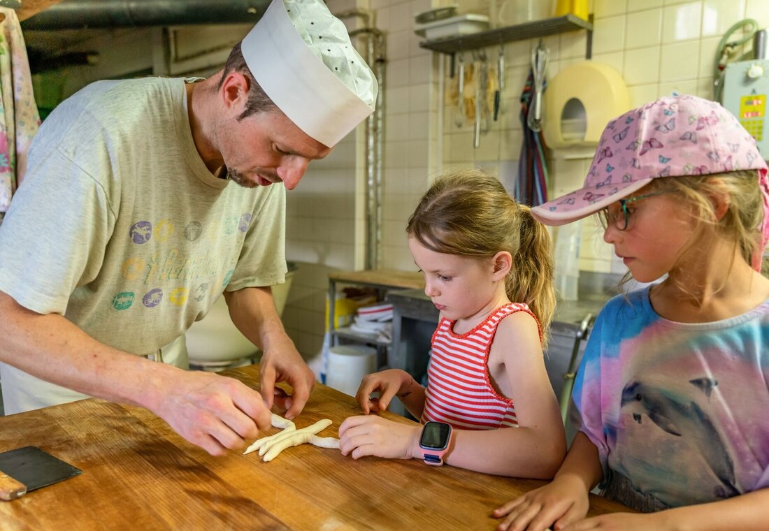 Zwei Kinder und ein Mann backen in der Bäckerei