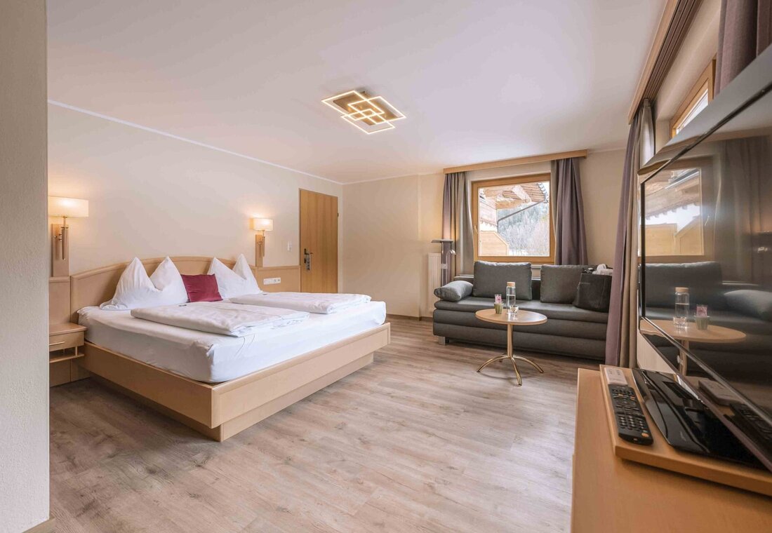 Großes Hotelzimmer mit Doppelbett und schwarzer Couch