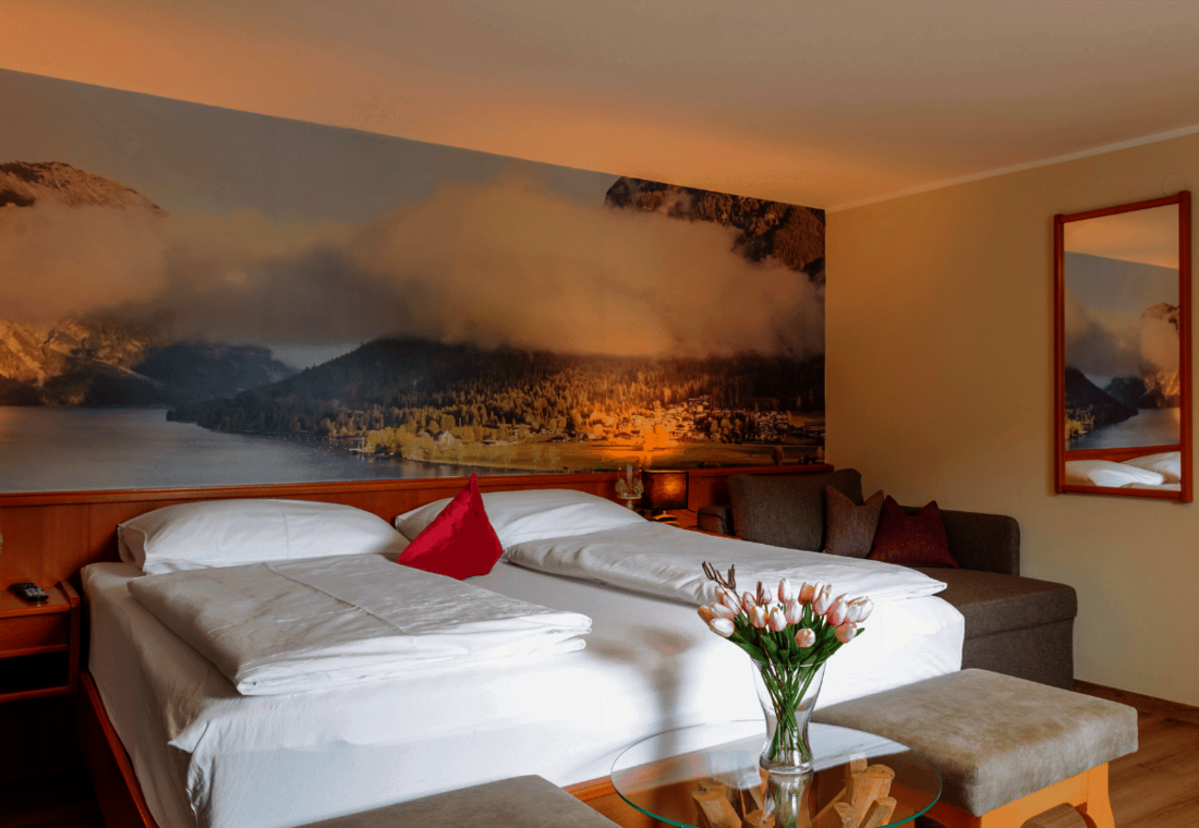 Doppelbett mit Spiegel an der Wand und Sitzgelegenheit